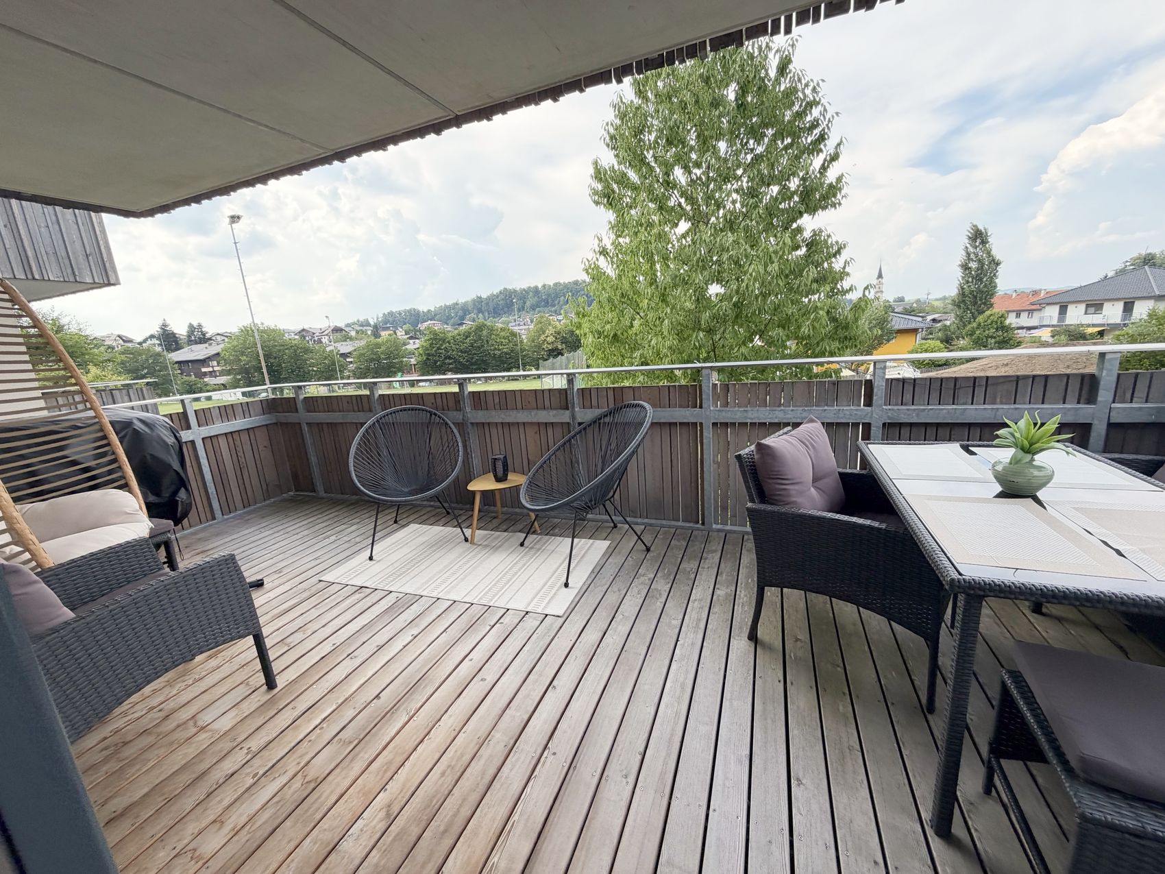 Weitläufiger Balkon mit Esstisch, Loungebereich und Blick über Mattsee